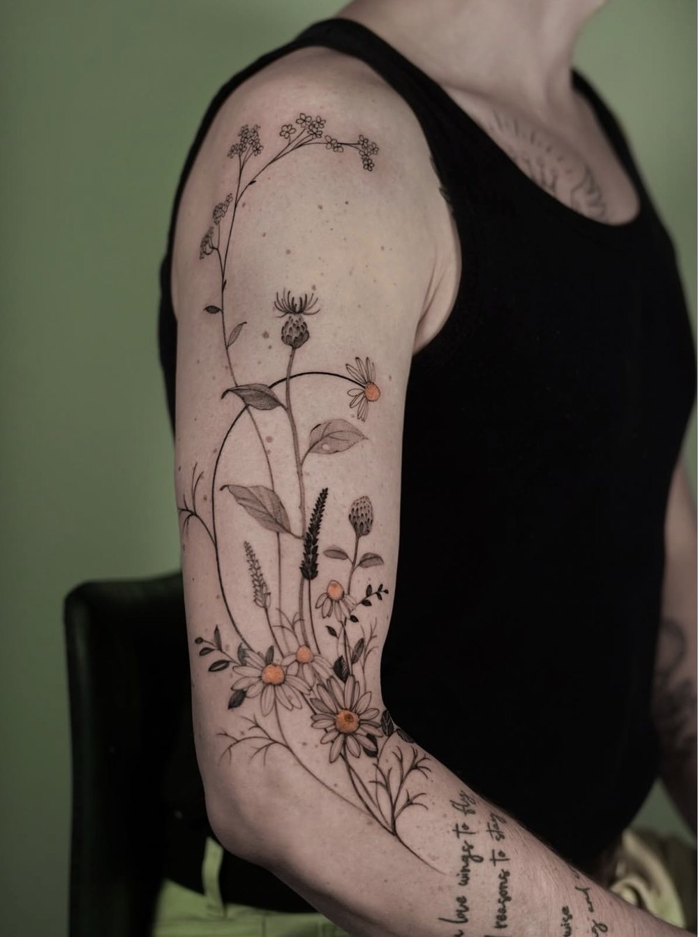 Wiesenblumen und Margeriten mit orangen Akzenten, Fine Line Tattoo Oberarm, von Misha, Velvet Line Karlsruhe